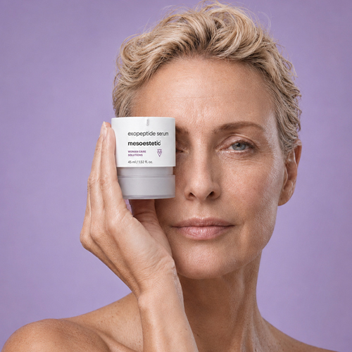 Model houdt Mesoestetic exopeptide serum voor haar oog tegen lichte paarse achtergrond
