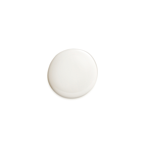 Een ronde, gladde druppel van een vloeibare, licht beige cosmetische crème op een witte achtergrond. De druppel is egaal en heeft een lichte glans.