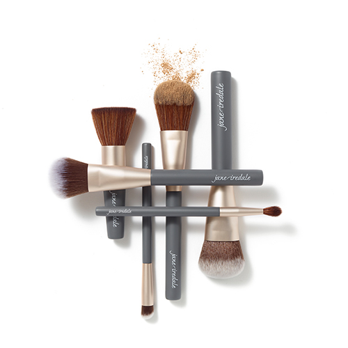 Jane Iredale kwasten overzicht op een witte achtergrond met losse poeder.
