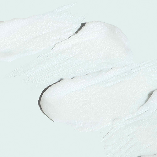 Detailopname van de witte exfoliërende crème met fijne micro-kristallen voor een peeling effect.