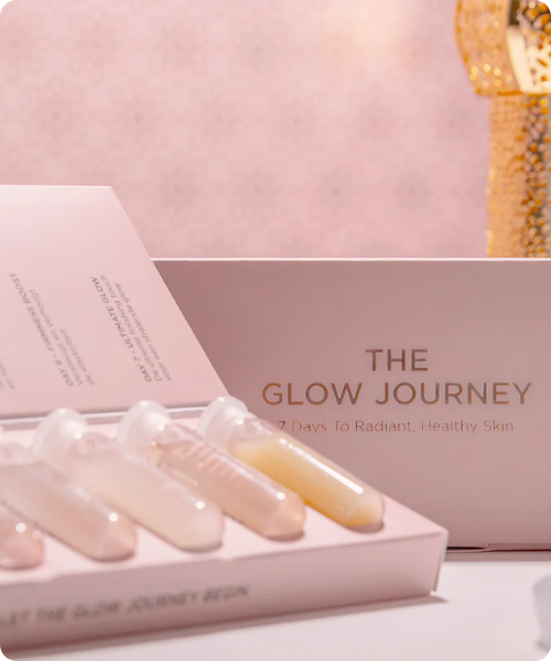 Een geopende lichtroze doos van D Skin met de tekst The Glow Journey waarin vier glazen ampullen met verschillende vloeistoffen liggen voor een 7 daagse huidverzorgingskuur