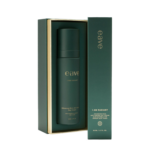 De Eave I AM RADIANT Day Cream staat in de geschenkverpakking op een witte achtergrond. De doos is donkergroen met goudkleurige letters en een verticale gouden streep. De fles is zichtbaar in de doos.