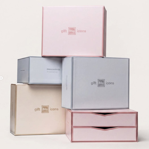 Stapel luxe Mesoestetic Gift Me Icons geschenkdozen in pastelkleuren op een lichte achtergrond