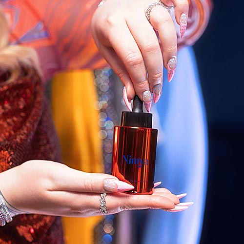 Handen houden het oranje serum flesje vast met de pipet in close-up