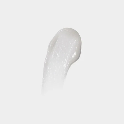 Textuur swatch van een zachte, romige witte crème op een egale grijswitte achtergrond