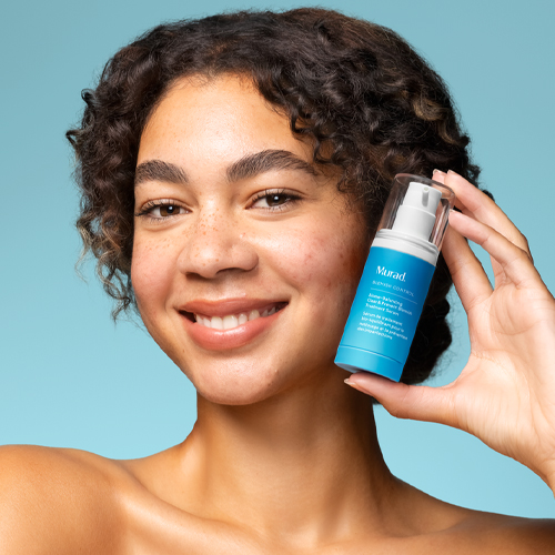 Vrouw met krullend haar toont de Murad Blemish Control Biome-Balancing Clear & Prevent Serum flacon