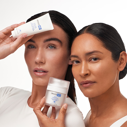 Twee modellen die de IMAGE Skincare MD Biotech Longevity Crème en de Barrier Repair Recovery Balm presenteren tegen een lichte achtergrond.