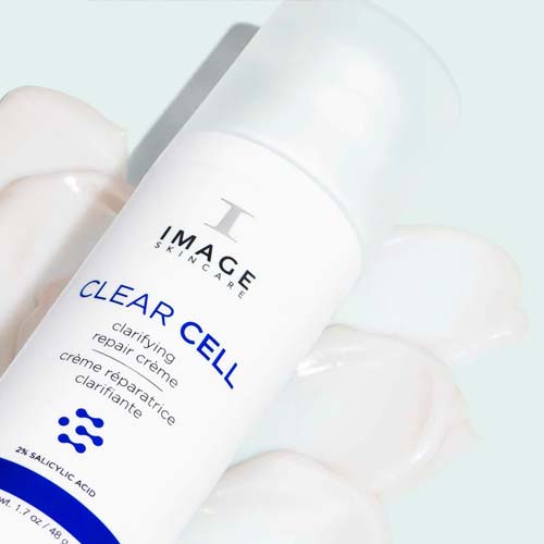 Sfeervolle close-up van de Clear Cell Clarifying Repair Crème flacon liggend op de uitgesmeerde crème-textuur
