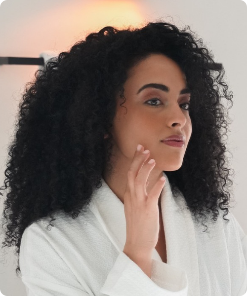 vrouw met krullen voelt aan haar gezicht voor hannah huidanalyse