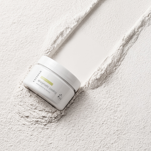 Witte pot Extenso Enzymatic Peeling liggend in een textuur van fijn wit poeder.