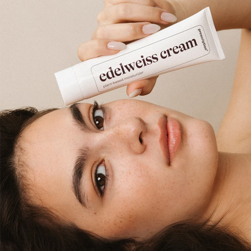 Vrouw die ligt en een tube Prescription edelweiss cream bij haar gezicht houdt