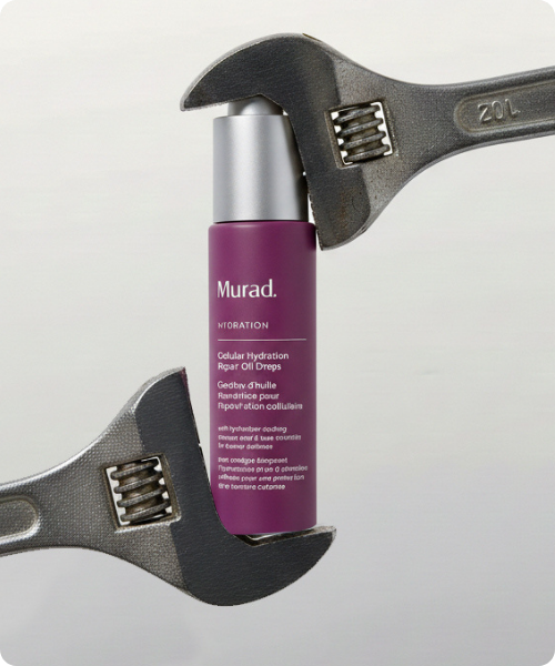 Een paarse flacon Murad Cellular Hydration Repair Oil Drops wordt vastgehouden door twee moersleutels