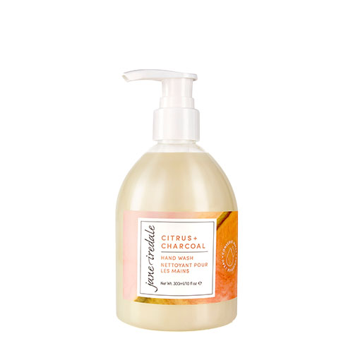 Een pompflacon van Jane Iredale Citrus + Charcoal Hand Wash op een witte achtergrond. De transparante huls toont de zachtgele vloeibare handzeep en het etiket met het merklogo