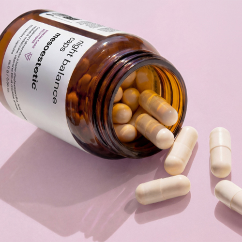 Omgevallen bruine pot met Mesoestetic night balance capsules en uitlopende supplementen