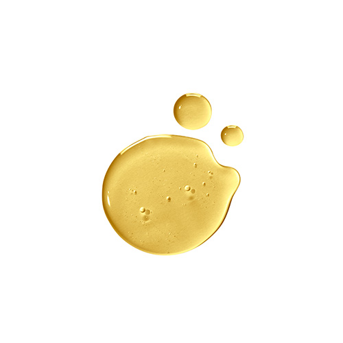 Drie glanzende druppels van de goudgele Natura Bissé Diamond Extreme Oil op een witte achtergrond.