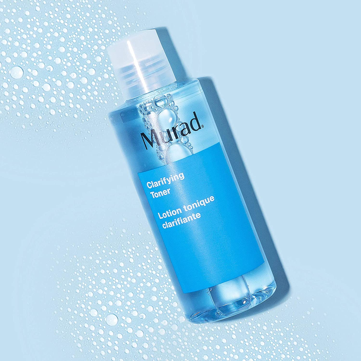 Murad Clarifying Toner flacon tegen een blauwe achtergrond met waterdruppels