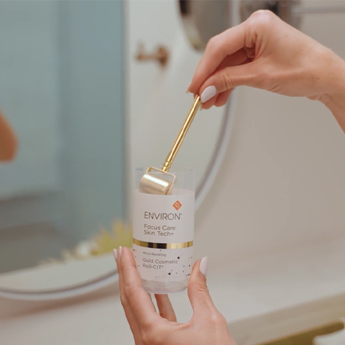 Sfeerbeeld van een hand die de gouden Environ Gold Cosmetic Roll-CIT reinigt in de daarvoor bestemde flacon met reinigingsvloeistof.