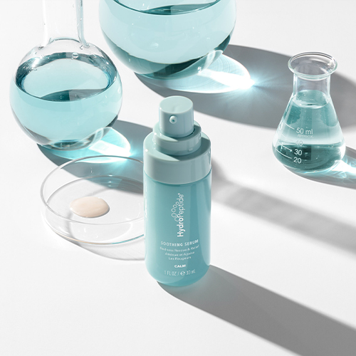 HydroPeptide Soothing Serum flacon omringd door laboratoriumglaswerk met blauwe vloeistof