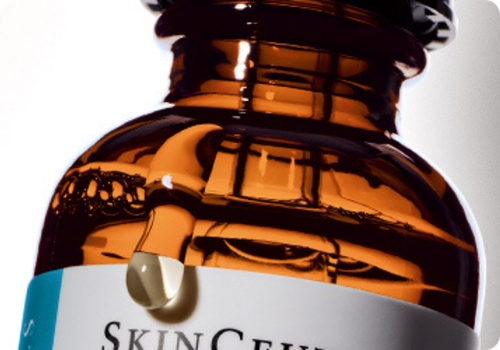 Een bruine amberkleurige fles van Skinceuticals met een druppel serum om huidveroudering te voorkomen