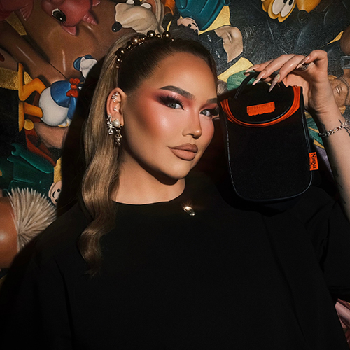 NikkieTutorials houdt de lichtblauwe Nimya Cosmetic Bag dicht bij haar gezicht terwijl ze lacht.