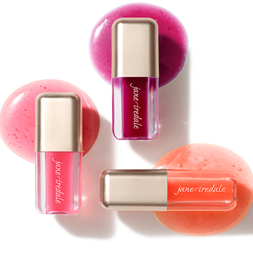 Drie flacons lipolie gepresenteerd op roze en oranje gekleurde cosmetische texturen