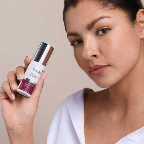 Sfeerbeeld van een model dat een flacon van het Environ Focus Care Youth+ Retinol Serum dicht bij haar gezicht vasthoudt.