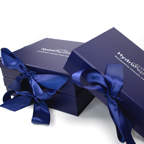 Twee gesloten donkerblauwe HydroPeptide geschenkdozen versierd met een opvallende blauwe strik