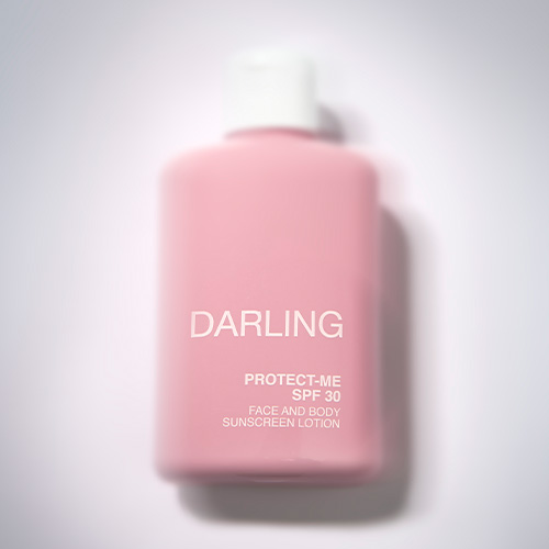 Een licht vervaagde, artistieke weergave van de roze DARLING PROTECT-ME SPF 30 flacon met zachte schaduwen.