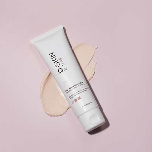 Een tube D-SKIN Cell Renewing Mask ligt schuin op een roze achtergrond met een beetje van het crèmekleurige masker ernaast uitgesmeerd.