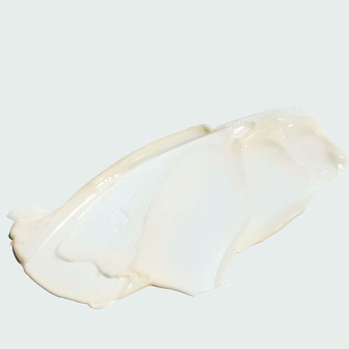 Een close-up van de rijke, witte crème-textuur van het IMAGE MD Restoring Youth Serum uitgesmeerd op een lichte achtergrond.