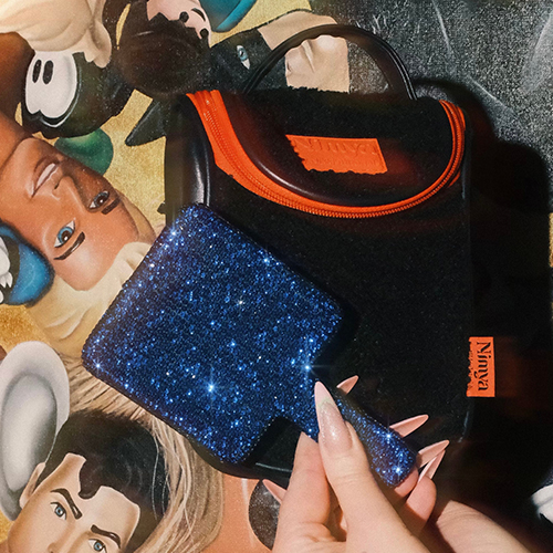 Een sfeerbeeld van de Nimya Cosmetic Bag geplaatst op een glanzend oppervlak met artistieke belichting.