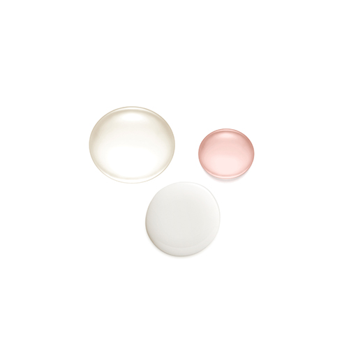 Drie verschillende vloeibare texturen van de Natura Bissé Diamond Instant Glow ampullen, variërend van transparant tot melkachtig wit.