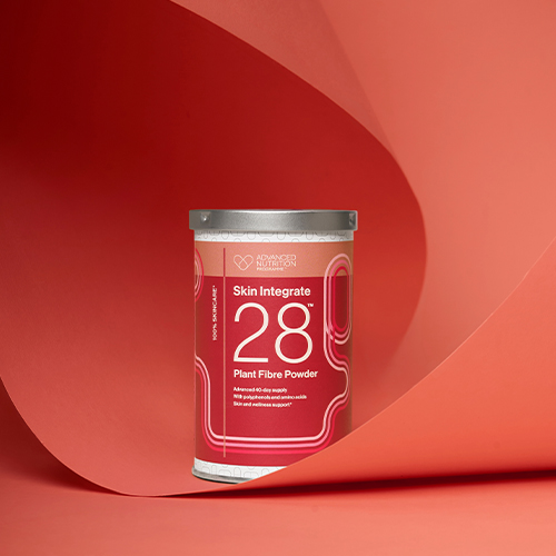 Een bus Skin Integrate 28 vezelpoeder geplaatst in een sfeervolle setting met gebogen rode en roze achtergronden.