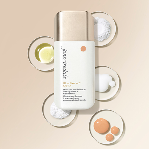 Jane Iredale Glow Fixation flesje omringd door schoteltjes met ingrediënten zoals poeder en vloeistoffen