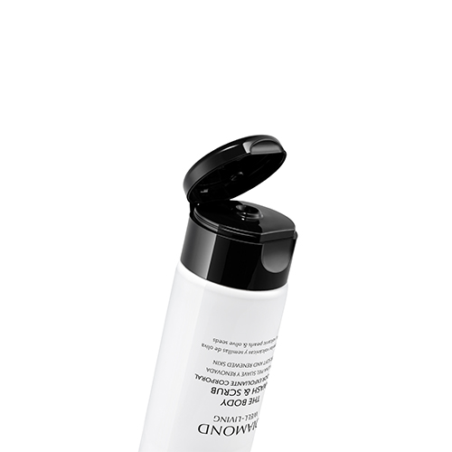 Een schuine close-up van de zwarte klikdop van de Natura Bissé The Body Wash & Scrub tube, die open staat om de opening en het witte, korrelige product binnenin te onthullen. De tube is wit met zwarte tekst. De achtergrond is zuiver wit.