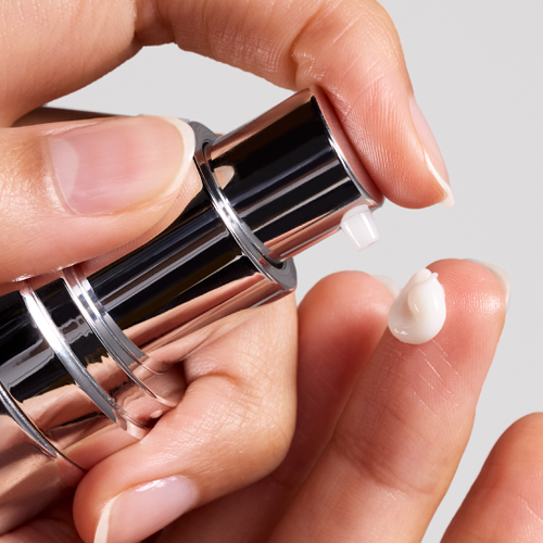 Close-up van een hand die de pomp van de iS Clinical Daily Dynamic Hydrator indrukt met een druppel crème op de vingertop