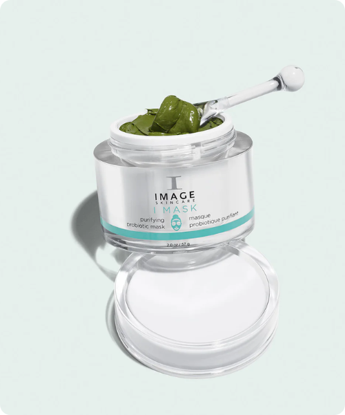 Een geopende pot Image Skincare I MASK Purifying Probiotic Mask gevuld met een groen kleimasker en een spatel.