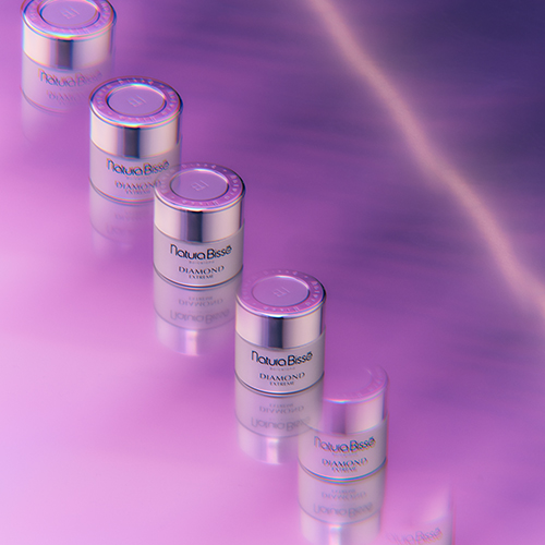 De Natura Bissé Diamond Extreme Light Texture crème stijlvol gepresenteerd naast een decoratieve zwarte schijf en natuurlijke elementen.