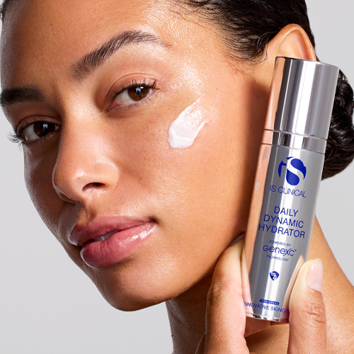 Model houdt de iS Clinical Daily Dynamic Hydrator flacon vast met een veeg gezichtscrème op haar wang