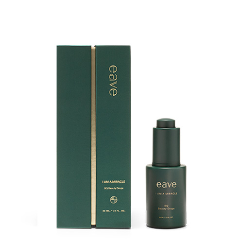 Het groene serumflesje van EAVE staat naast de bijbehorende luxe, donkergroene verticale verpakking met gouden details.