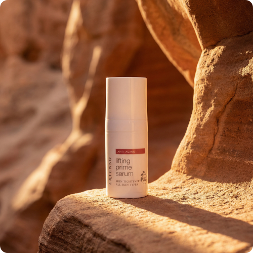 De flacon van Extenso Anti Aging lifting prime serum staat op een rotsachtige ondergrond in warm, natuurlijk zonlicht.