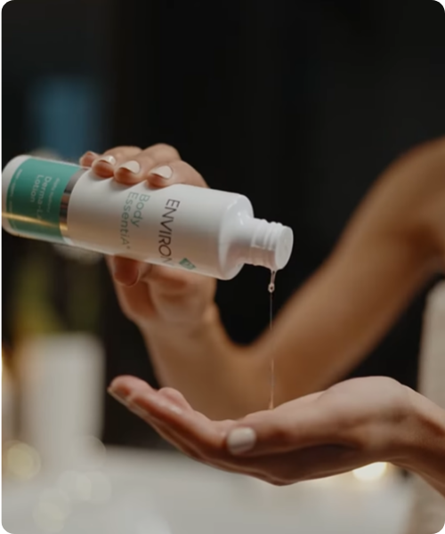 Een sfeerbeeld waarin een vrouw de Environ Body EssentiA Derma-Lac Lotion in haar handpalm giet. Dit sfeerbeeld met afgeronde hoeken wordt getoond in de afbeelding