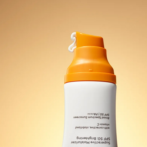 Close-up van het oranje pompje van de Murad Superactive Moisturizer SPF 50 met een toefje witte crème