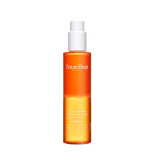 Een hoge, slanke oranje sprayflacon van Natura Bissé C+C Vitamin Bi-Phase Invisible Sunscreen SPF 50 met een witte dop.