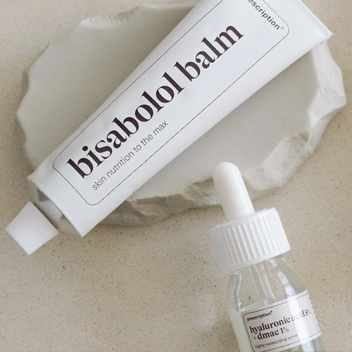 Tube bisabolol balm en een flesje hyaluronic acid op een decoratieve schaal