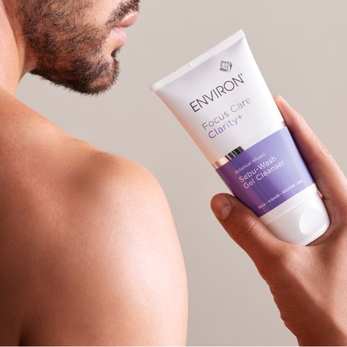 Sfeerbeeld van een man die de tube Environ Focus Care Clarity+ Sebu-Wash Gel Cleanser over zijn schouder vasthoudt