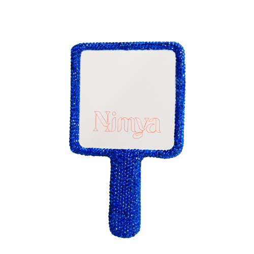 Een ronde, lichtblauwe handspiegel van Nimya met een ergonomisch handvat, gezien vanaf de spiegelkant.