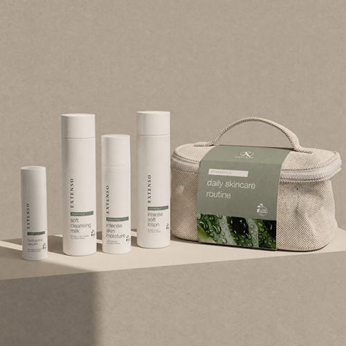 Extenso daily skincare routine essentials set met een zachte reinigingsmelk serum en hydraterende lotion geplaatst voor een beige toilettas