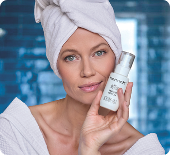 Een vrouw met een witte handdoek om haar hoofd houdt een flacon hannah prepare potion vast tegen een blauwe achtergrond