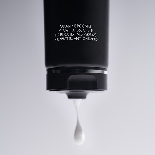 Een close up van een zwarte tube Marc Inbane Body Lotion waar een druppel witte lotion uitloopt